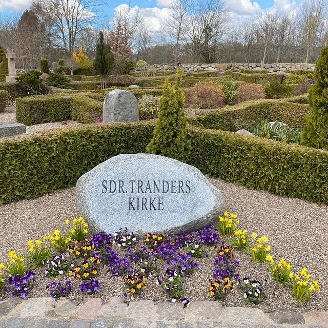 Sten og blomster på kirkegården ved Sønder Tranders Kirke